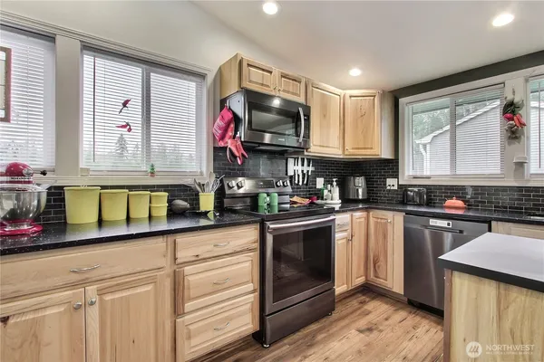 a kitchen with granite countertop a sink stainless steel appliances and cabinets