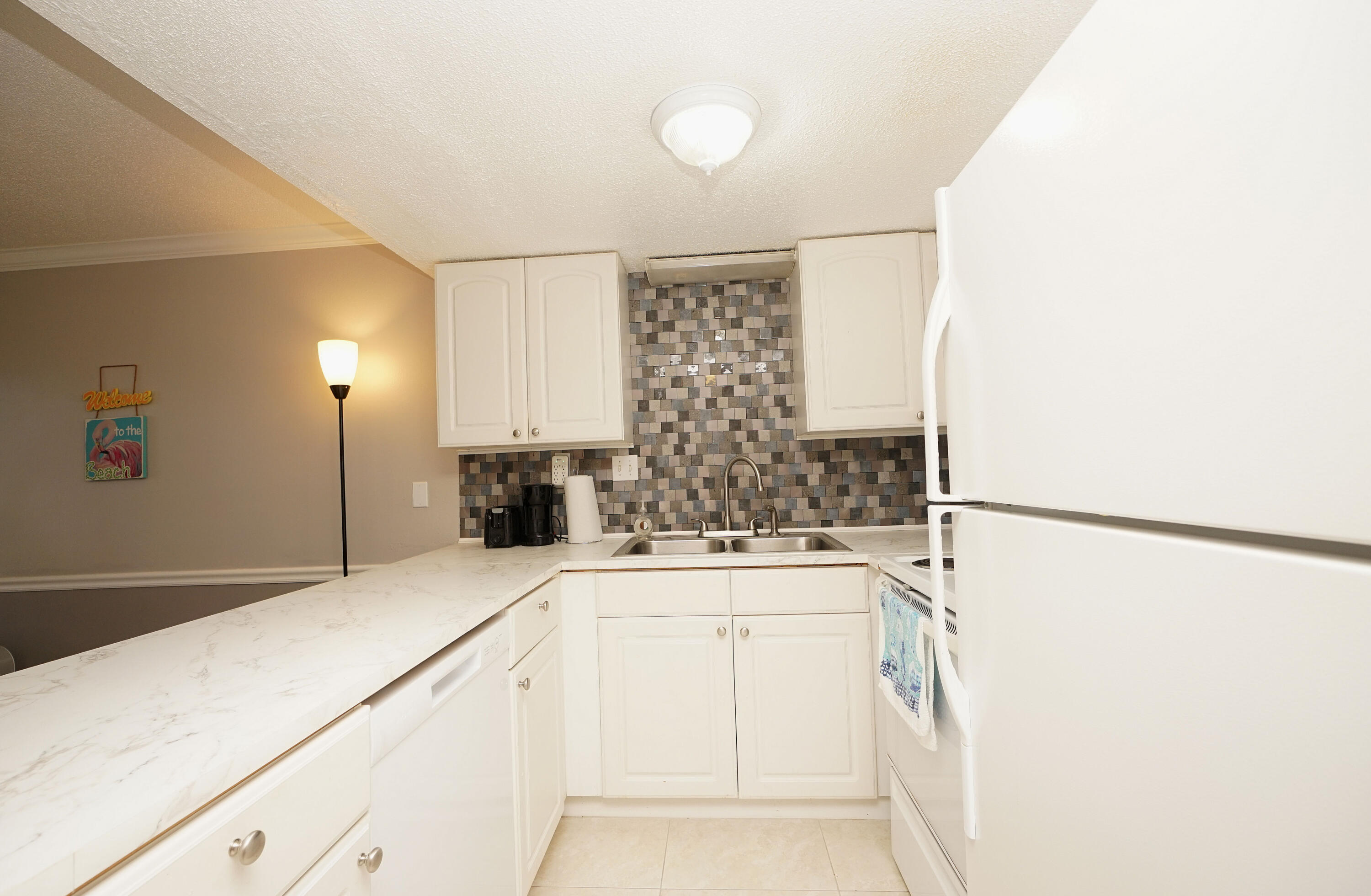 308 Miracle Strip Parkway Southwest, Unit 7D Fort Walton Beach, FL 32548 - Photo 11 of 34 a kitchen with a refrigerator and a sink