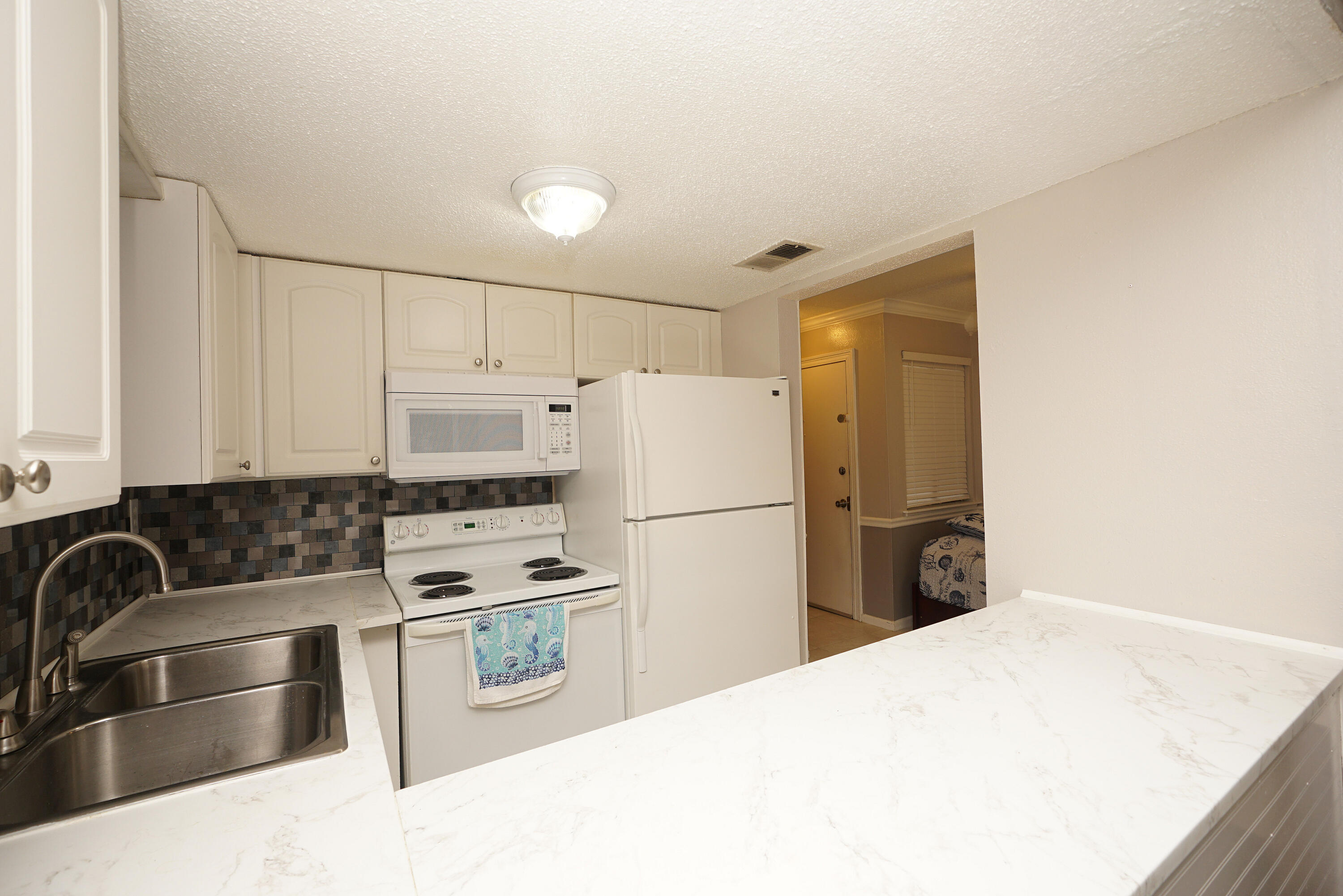 308 Miracle Strip Parkway Southwest, Unit 7D Fort Walton Beach, FL 32548 - Photo 12 of 34 a kitchen with a refrigerator sink and white cabinets