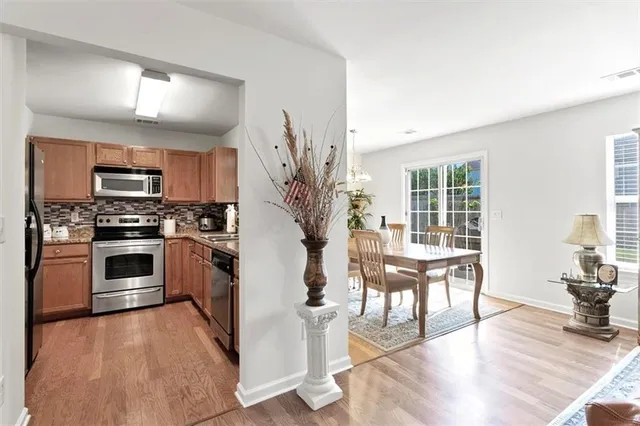 a kitchen with granite countertop a stove top oven a sink dishwasher a dining table and chairs with wooden floor