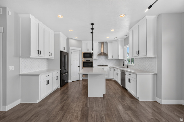 36 West Syracuse Road Vineyard, UT 84059 - Photo 17 of 56 Spacious kitchen featuring white cabinetry, a large central island, stainless steel appliances, herringbone tile backsplash, and wood-finish flooring