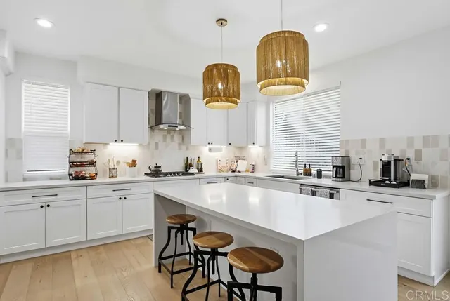 a kitchen with stainless steel appliances a table chairs in it and wooden floors