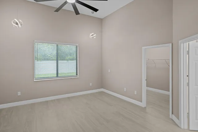 an empty room with a window and ceiling fan