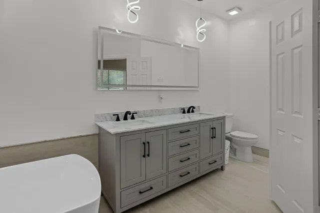 a bathroom with a double vanity sink mirror and toilet