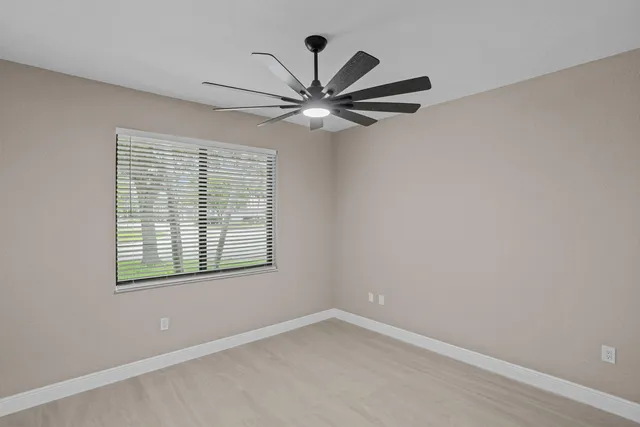 an empty room with windows and fan