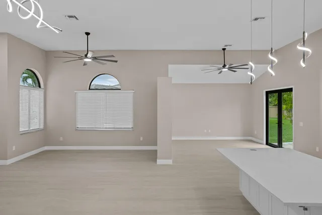 an empty room with windows and ceiling fan