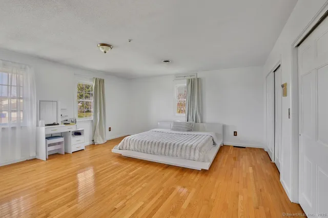 a spacious bedroom with a bed and dresser with wooden floor
