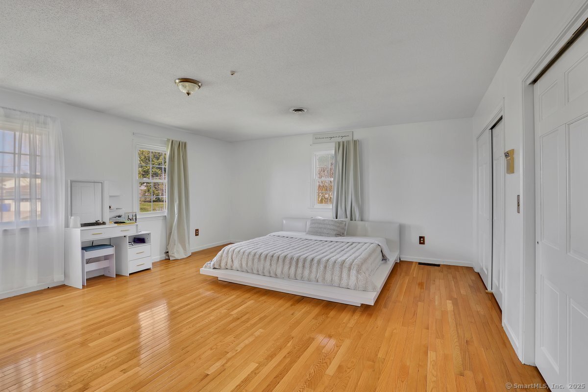 96 Neill Drive Watertown, CT 06795 - Photo 13 of 20 a spacious bedroom with a bed and dresser with wooden floor