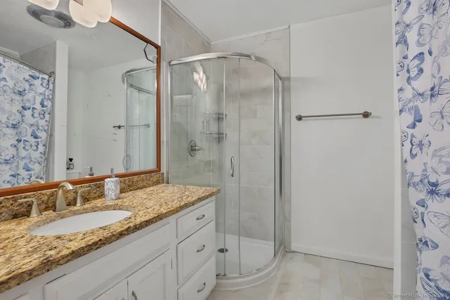a bathroom with a granite countertop sink a mirror and shower