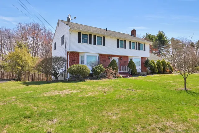 a front view of house with yard and trees in the background
