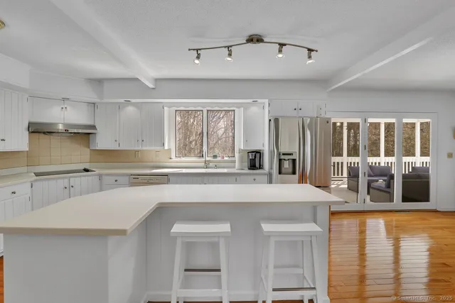 a kitchen with stainless steel appliances granite countertop a stove a sink dishwasher and a refrigerator with wooden floor