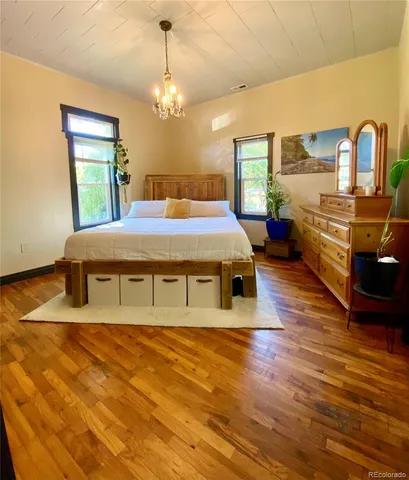 a spacious bedroom with a bed dresser and wooden floor