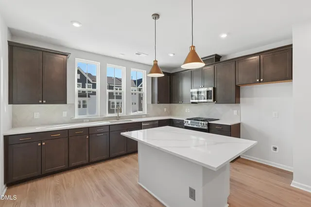 a large kitchen with granite countertop a large counter top stainless steel appliances and wooden floor