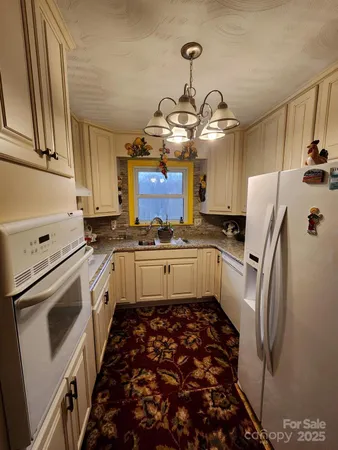 a kitchen with stainless steel appliances a stove a refrigerator and a chandelier