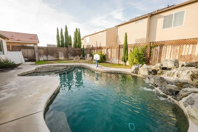 a swimming pool with outdoor seating and a shower