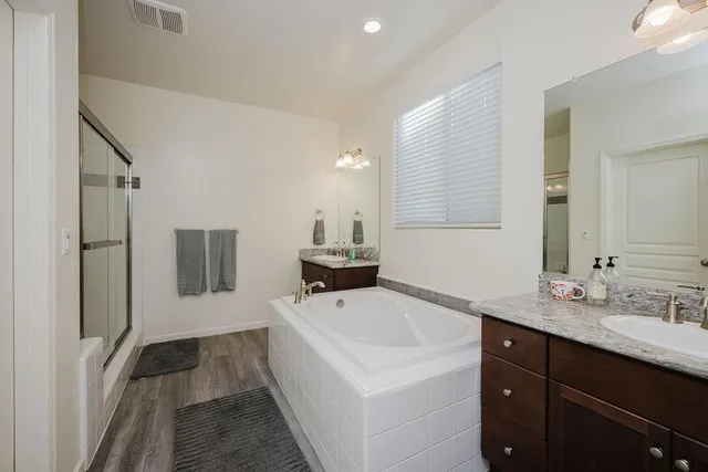 a en suite spacious bathroom with a tub double vanity and mirrors