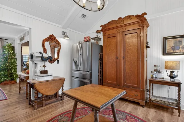 a kitchen with stainless steel appliances granite countertop a stove a refrigerator a dining table and chairs with wooden floor