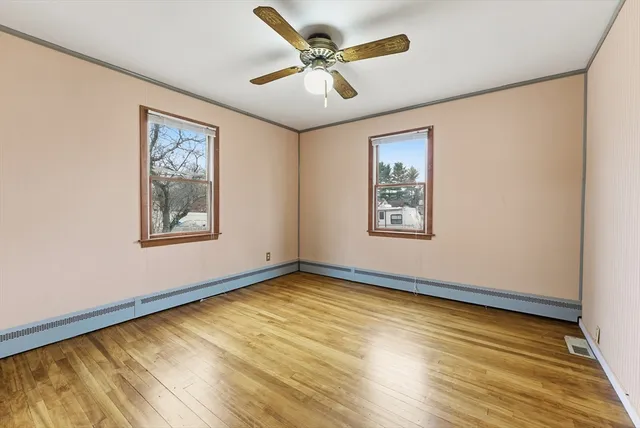 a view of an empty room with window and wooden floor