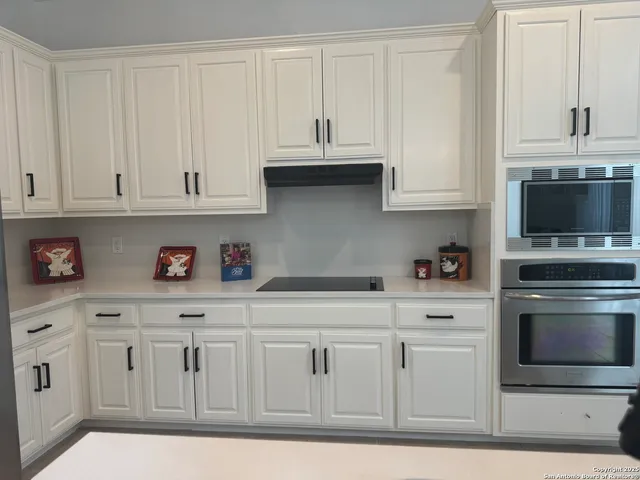 a kitchen with white cabinets and stainless steel appliances