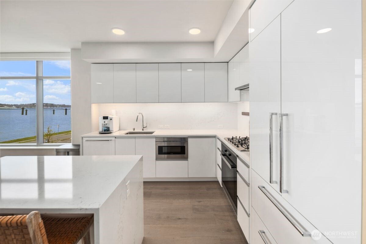 1250 Alki Avenue Southwest, Unit 3C Seattle, WA 98116 - Photo 8 of 31 a kitchen with kitchen island a counter top space a sink stainless steel appliances and cabinets