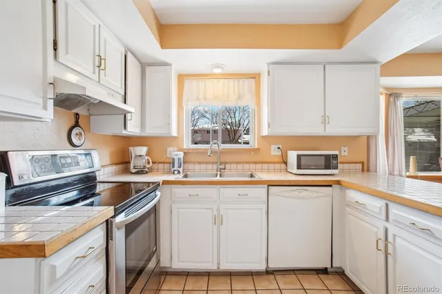 a kitchen with granite countertop white cabinets window and appliances