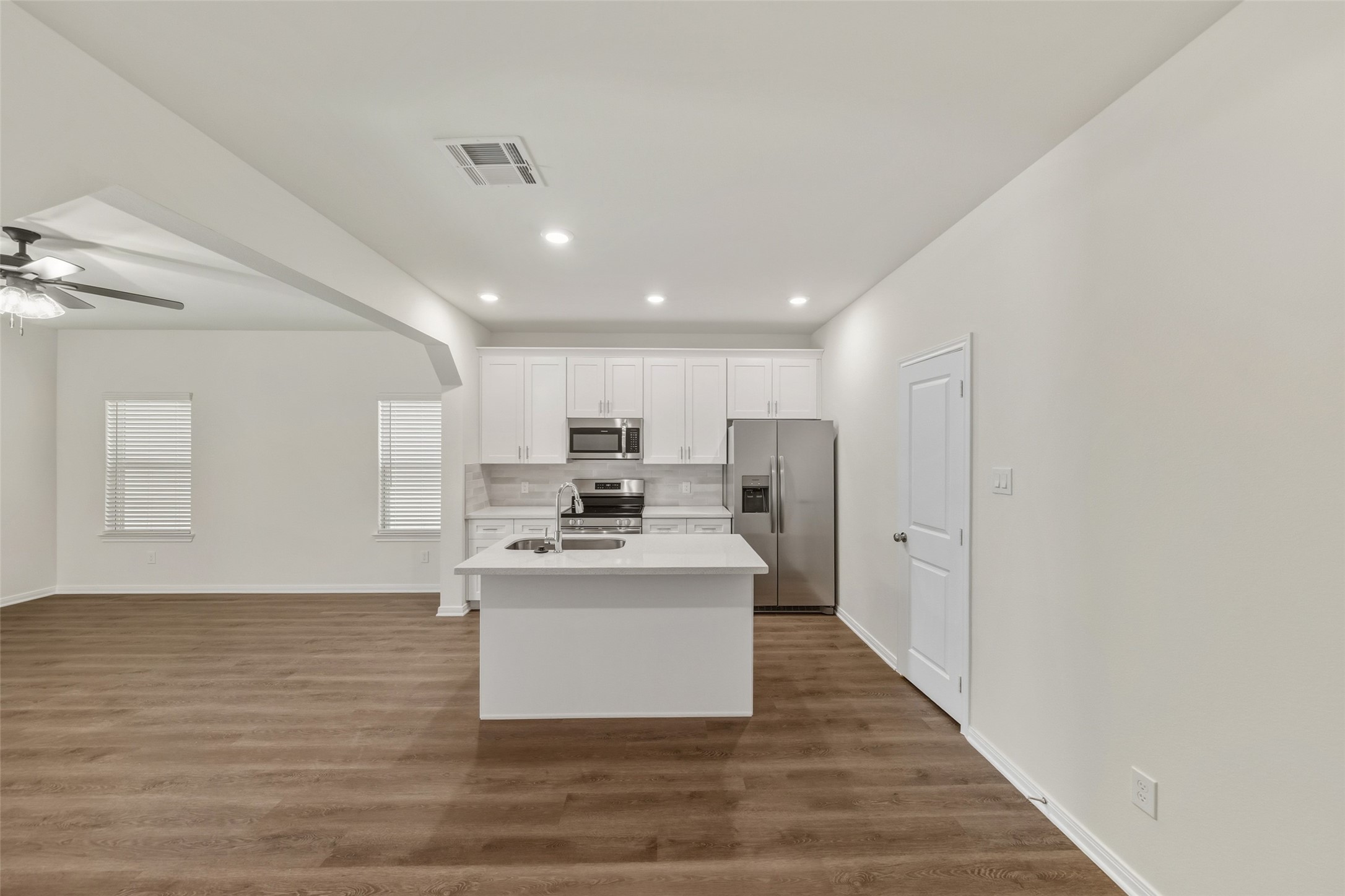 708 West Dallas Street Conroe, TX 77301 - Photo 10 of 19 a large white kitchen with kitchen island a stove a sink a refrigerator and white cabinets with wooden floor