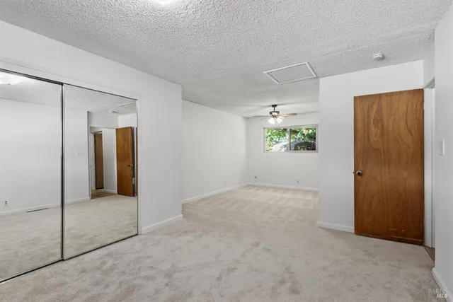 an empty room with windows and fan