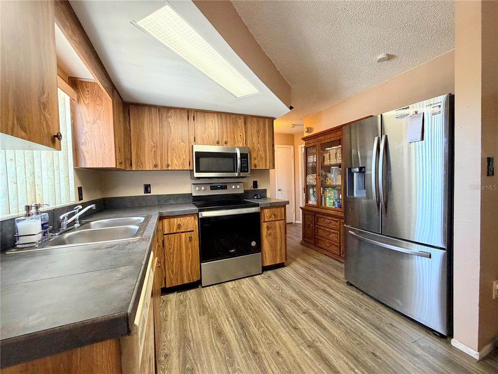 9840 Crofton Lane Port Richey, FL 34668 - Photo 6 of 12 a kitchen with wooden floors stainless steel appliances a sink and a window