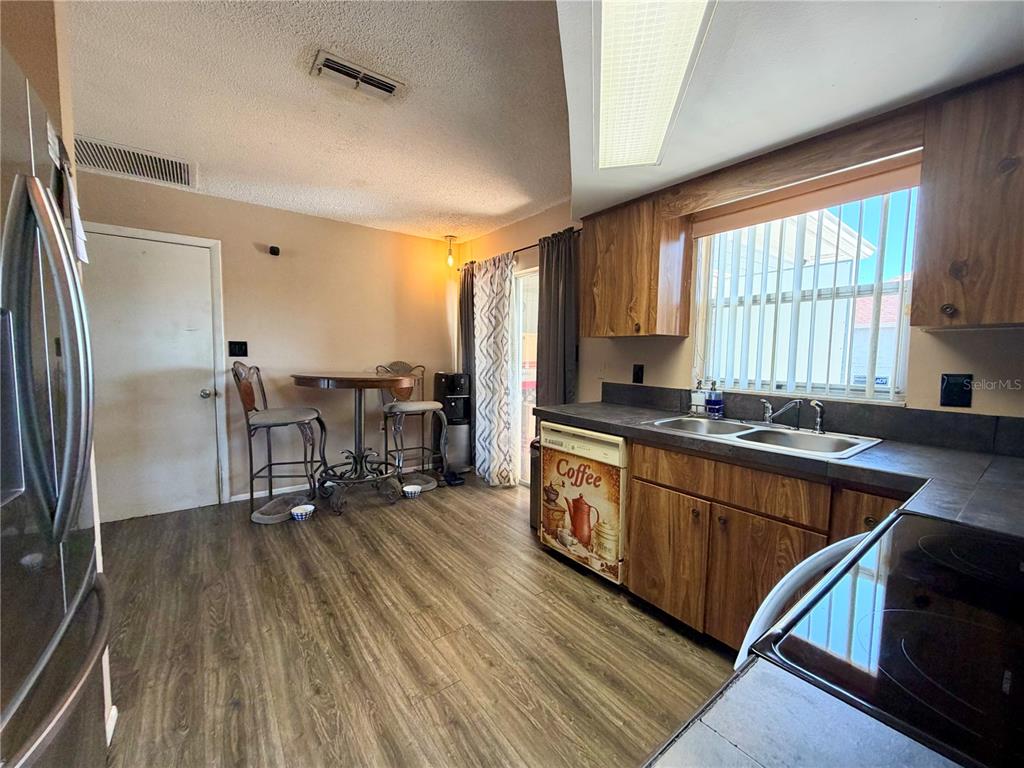 9840 Crofton Lane Port Richey, FL 34668 - Photo 7 of 12 a kitchen with stainless steel appliances granite countertop a refrigerator a sink dishwasher a stove and white countertops with wooden floor