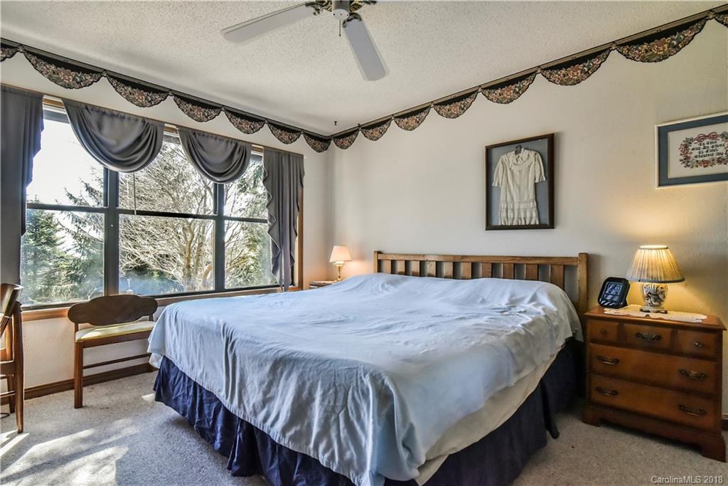 286 Pioneer Ridge Road Canton, NC 28716 - Photo 24 of 33 a bedroom with a bed a chandelier and a window
