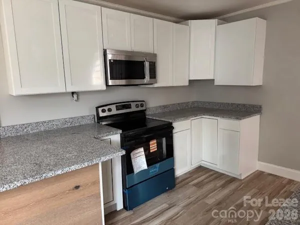 a kitchen with granite countertop a stove and a microwave
