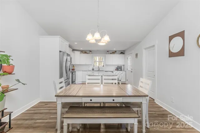a view of a kitchen with a stove a refrigerator and a dining table with wooden floor