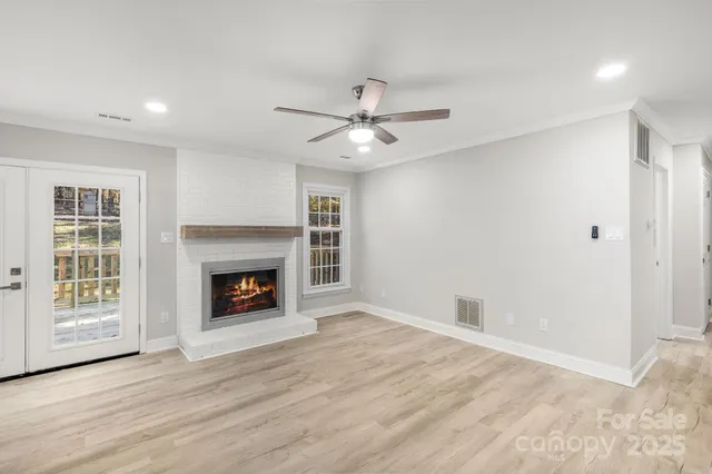 an empty room with windows fireplace and a kitchen view