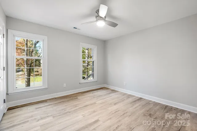 a view of an empty room with a window and wooden floor