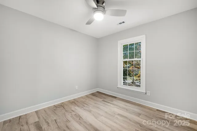 an empty room with windows and fan