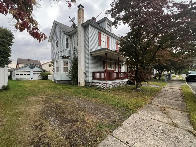a view of a white house that has a tree on the side of it