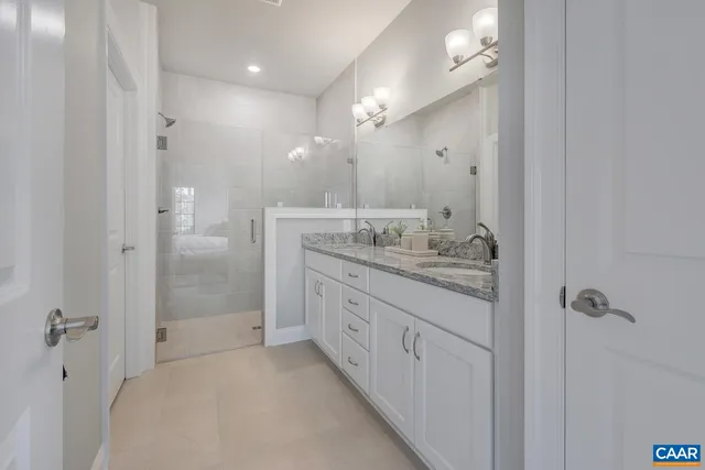 a bathroom with a granite countertop sink two mirror and shower