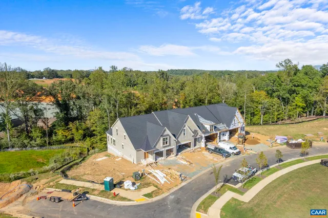a view of a white house with a big yard plants and large tree