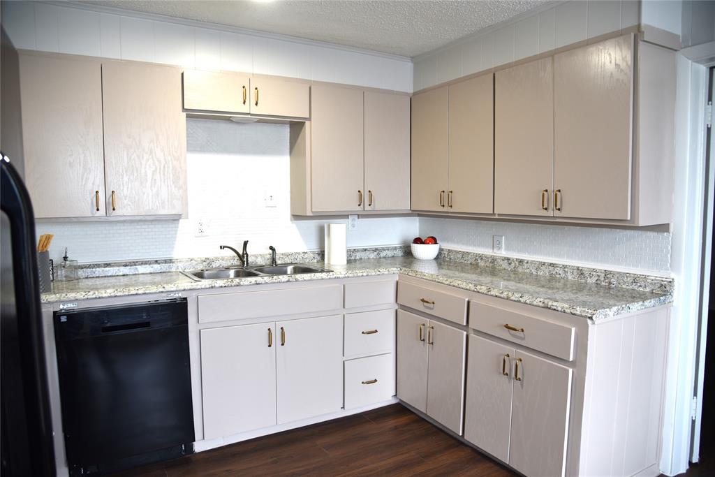 900 West Chestnut Street Denison, TX 75020 - Photo 5 of 22 a kitchen with granite countertop white cabinets and white appliances