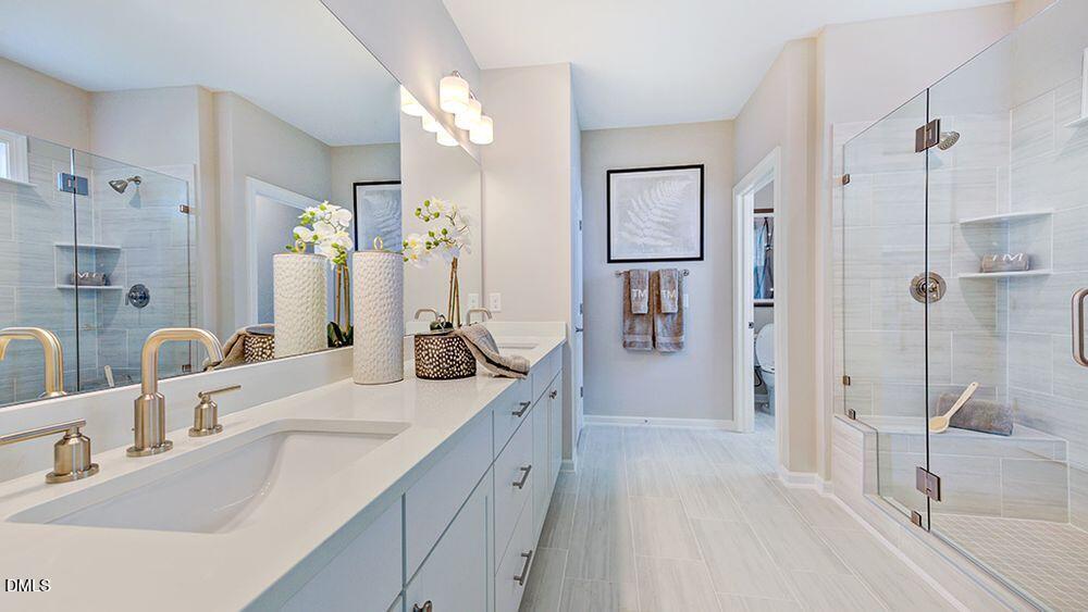 2000 Clydner Drive Apex, NC 27523 - Photo 20 of 36 a bathroom with a double vanity sink a mirror a shower and a bathtub