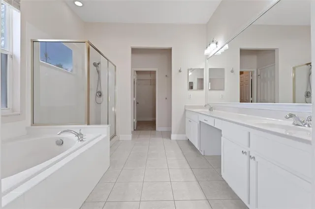 a view of an empty room with chandelier fan and kitchen view