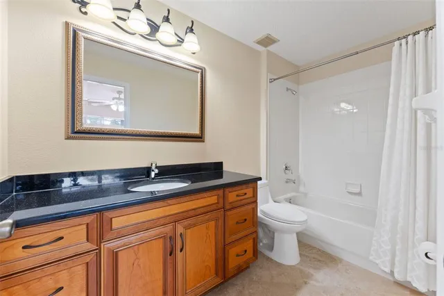 an empty room with windows and chandelier fan