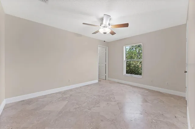 an empty room with a mirror and a ceiling fan
