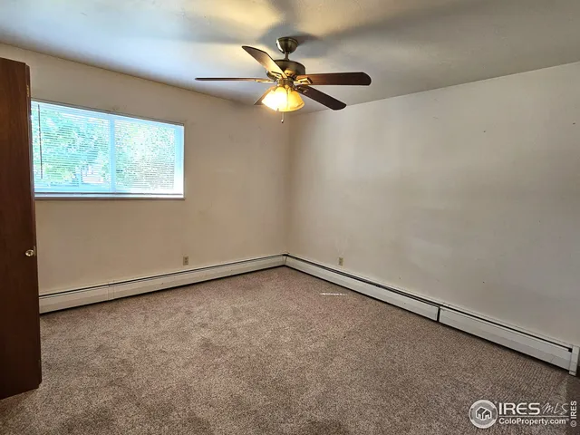 an empty room with a window and a fan