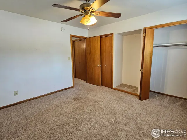 an empty room with closet and a chandelier fan