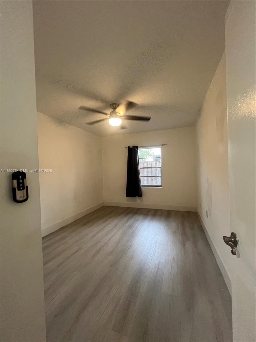 9621 Southwest 77th Avenue, Unit 108B Miami, FL 33156 - Photo 14 of 16 an empty room with wooden floor and windows