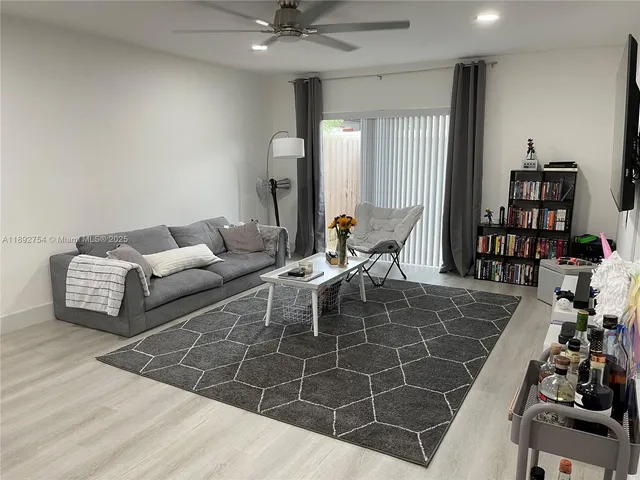 a living room with furniture a book shelf and a wooden floor