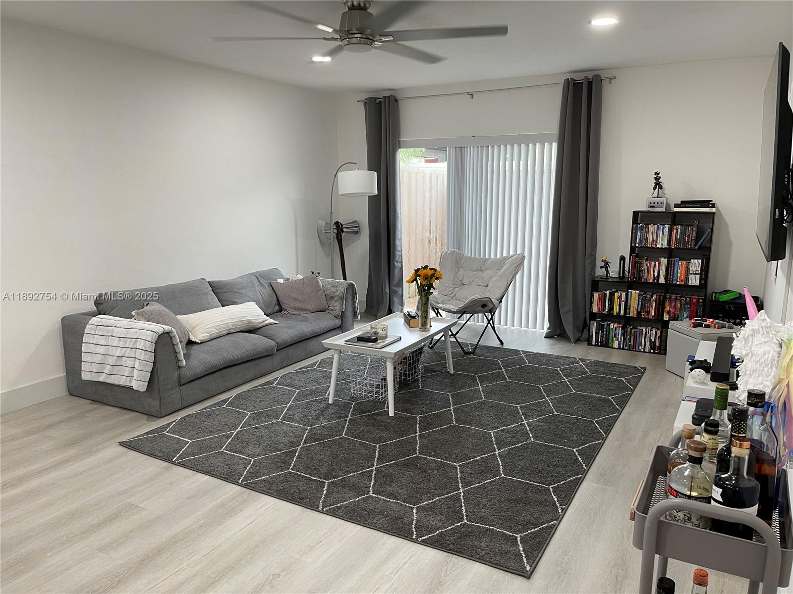 9621 Southwest 77th Avenue, Unit 108B Miami, FL 33156 - Photo 3 of 16 a living room with furniture a book shelf and a wooden floor