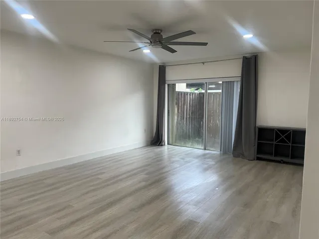 an empty room with wooden floor and a ceiling fan
