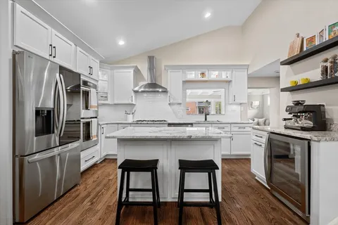 a kitchen with granite countertop white cabinets and stainless steel appliances